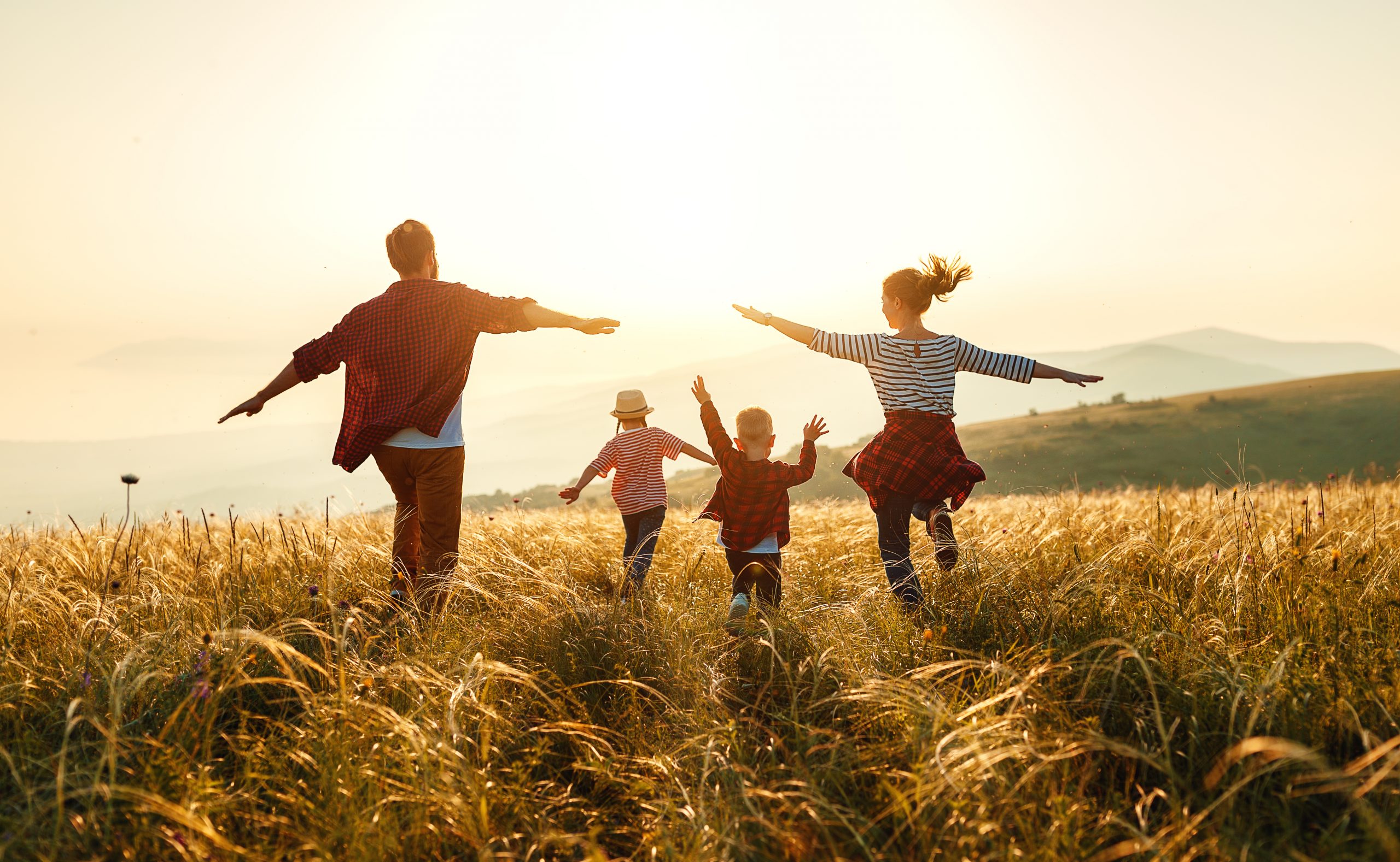Familia por el prado con el sol de fondo